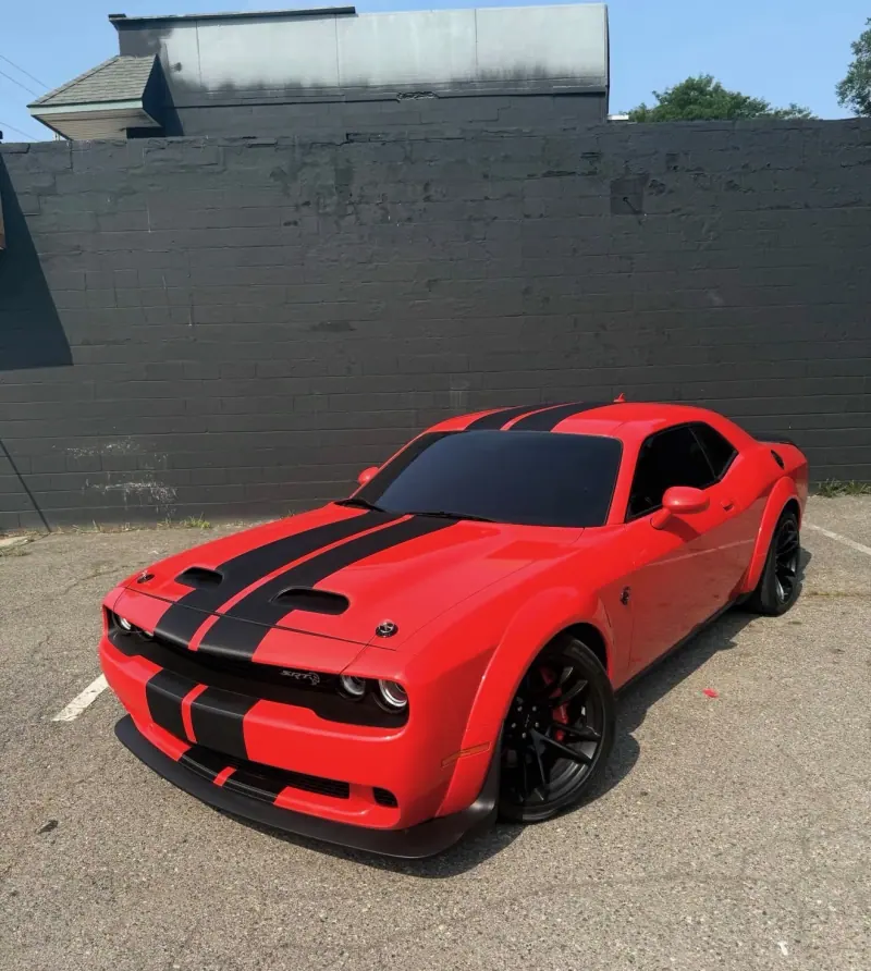 Red Dodge Challenger with black stripes, front three quarter view