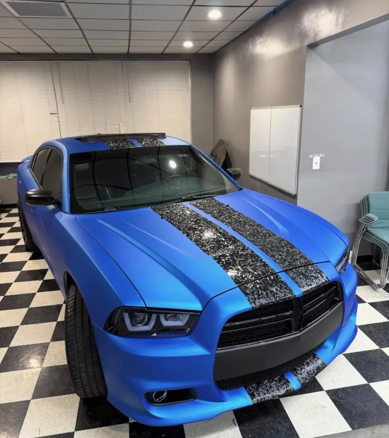 Blue Dodge Charger with forged carbon stripes on a checkered floor, front view