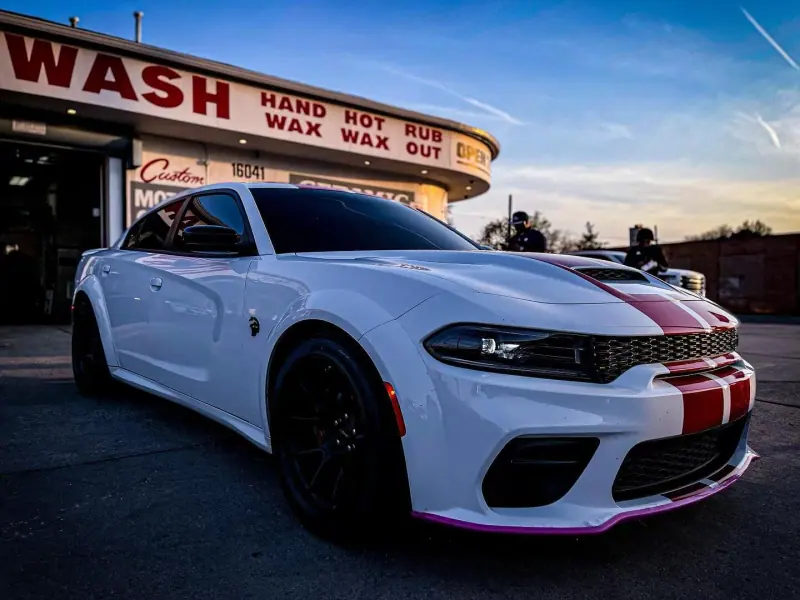 White Dodge Charger with red stripes, front three quarter view in the evening