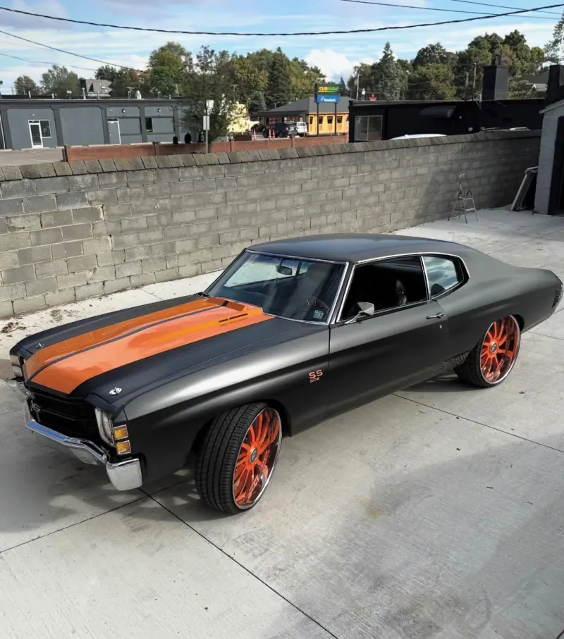 Matte black Chevy Chevelle with orange stripes and orange wheels, front three quarter view