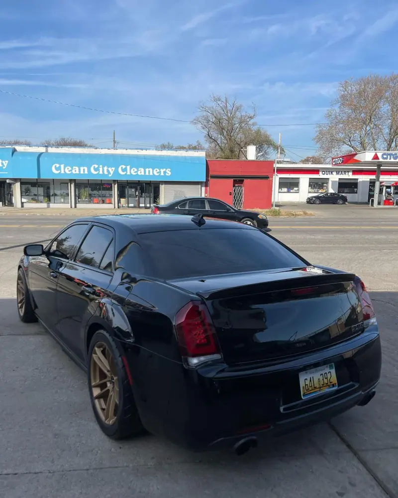 Black Chrysler 300 with bronze wheels, rear view on the street