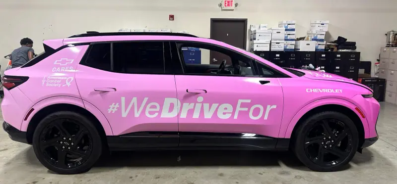 Pink Chevy Blazer EV in a WeDriveFor printed wrap inside the shop