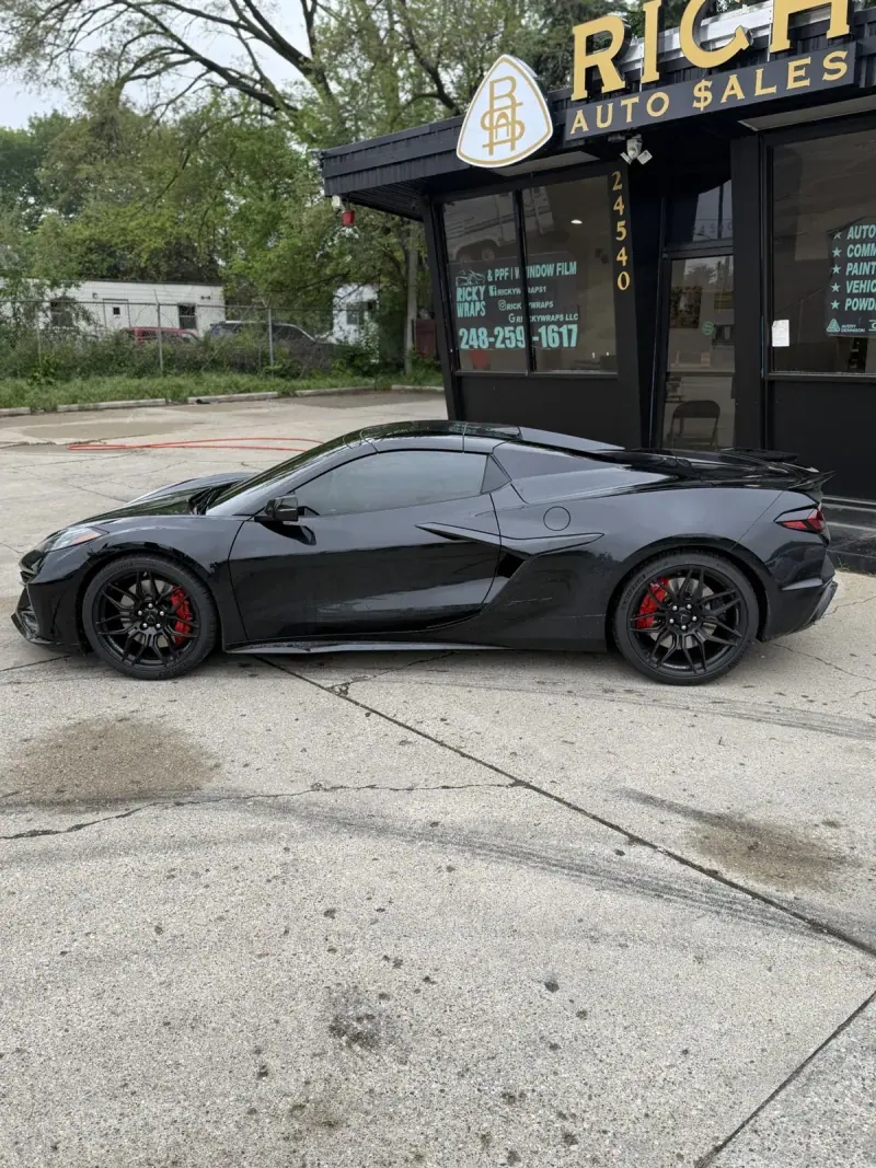 Black Chevy Corvette C8, wide view with a storefront behind