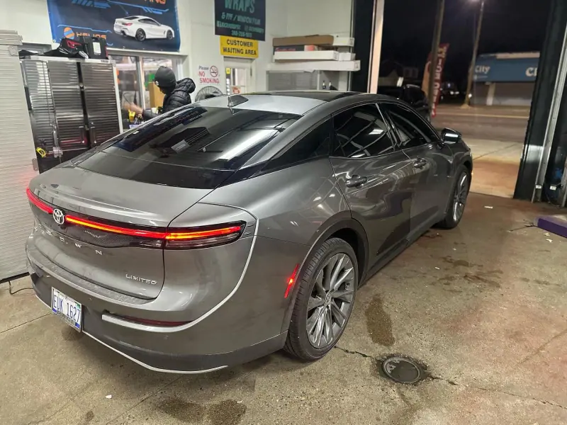 Gray Toyota Crown, rear three quarter view inside the shop at night