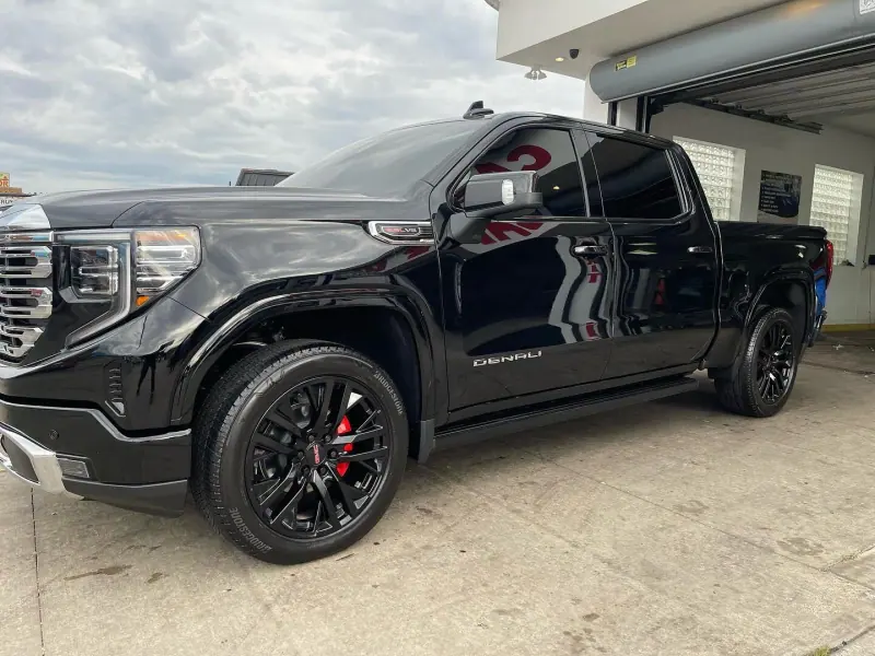 Gloss black GMC Denali pickup, front three quarter view