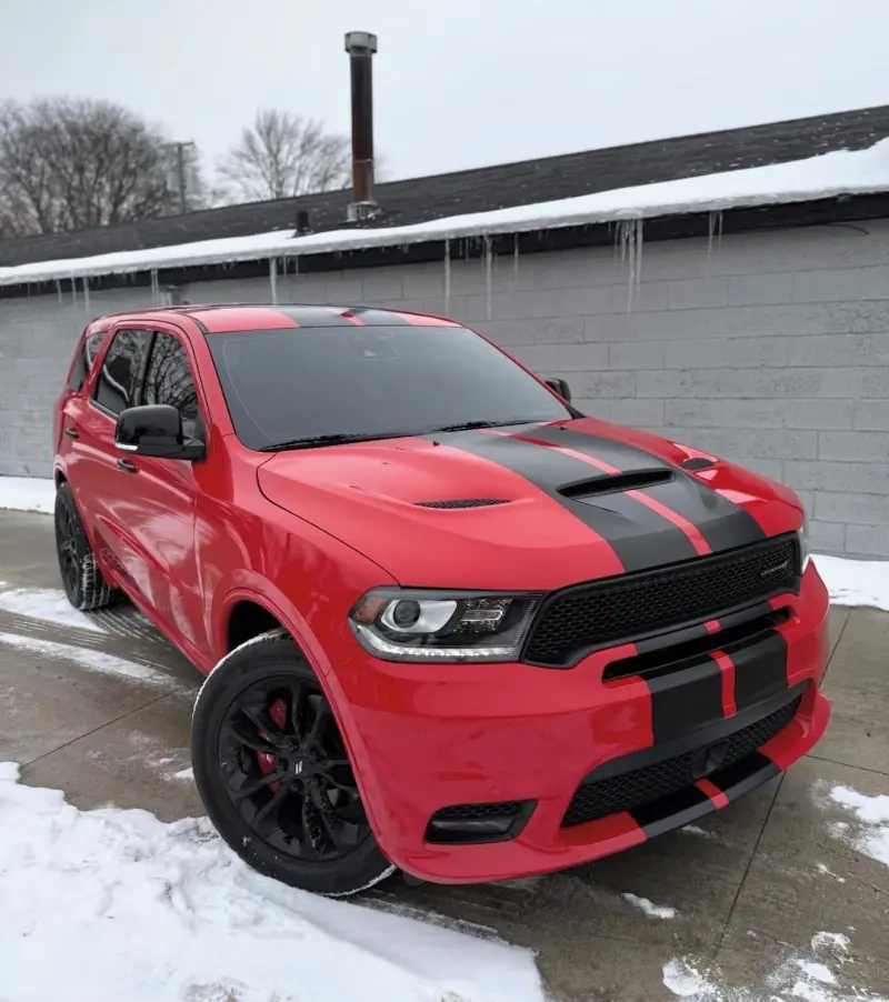 Red Dodge Durango with black stripes in the snow, front three quarter view