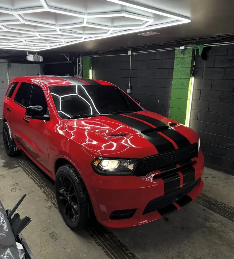 Red Dodge Durango with black stripes under hexagon lights inside the shop