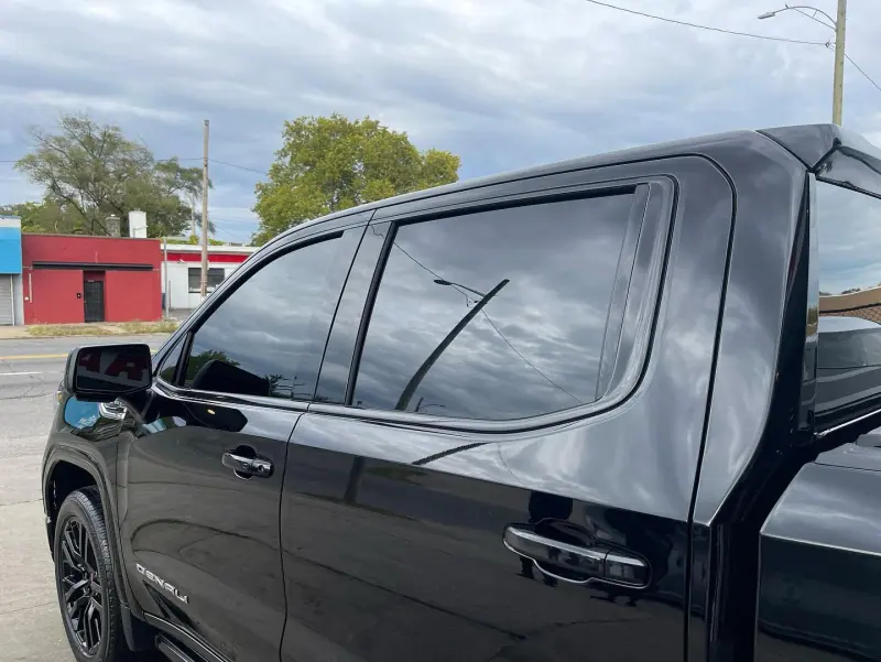 Tinted rear door glass on a black GMC Denali pickup, close up