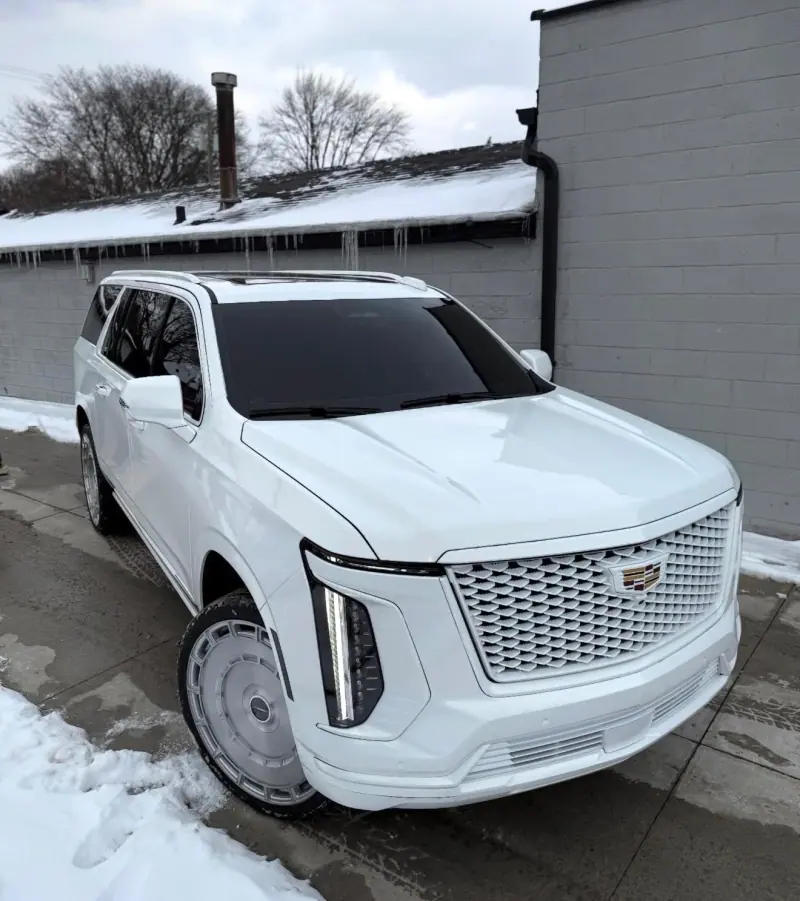 White Cadillac Escalade parked in the snow, front three quarter view
