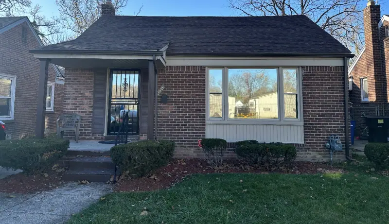 Brick house with window film on the front window, reflecting the street