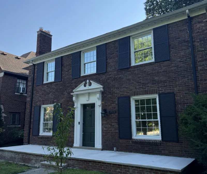 Two story brick home with window film on the front windows, seen from the side