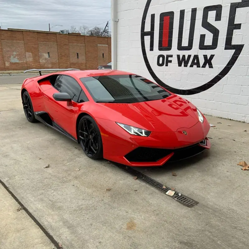 Red Lamborghini Huracan parked beside a white wall