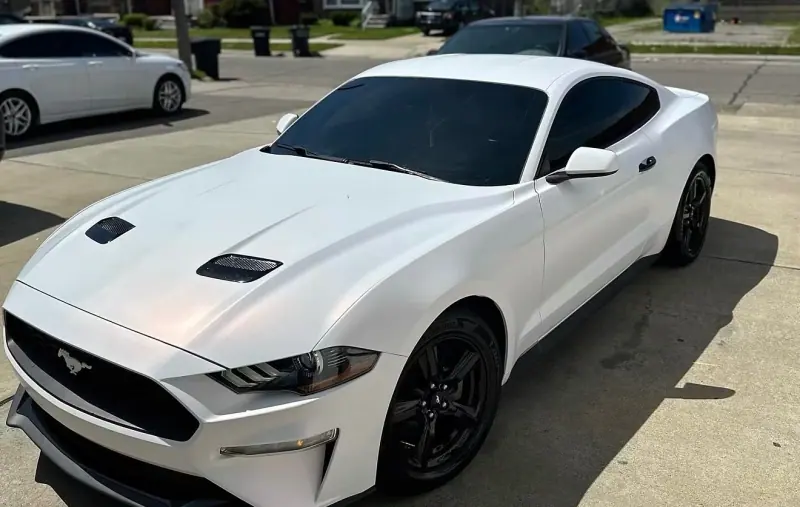 White Ford Mustang with black wheels, front three quarter view