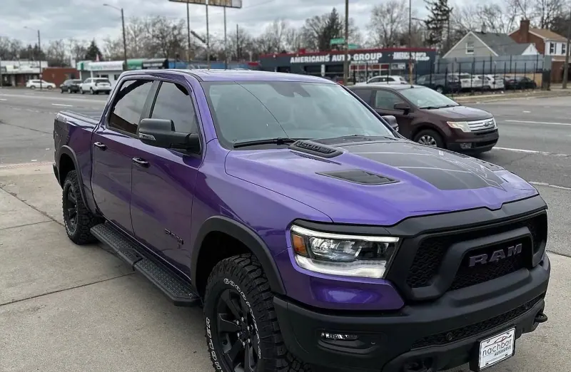 Purple Ram 1500 pickup with a black hood, front three quarter view on the street