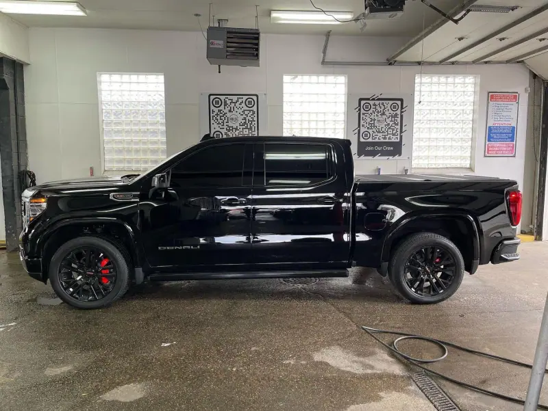 Gloss black GMC Denali pickup in a wash bay