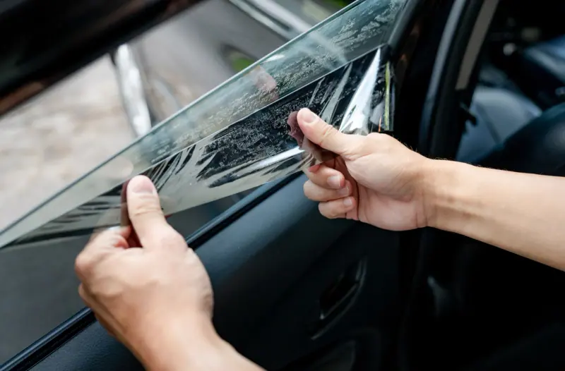 Window film being trimmed by hand on a door glass, close up