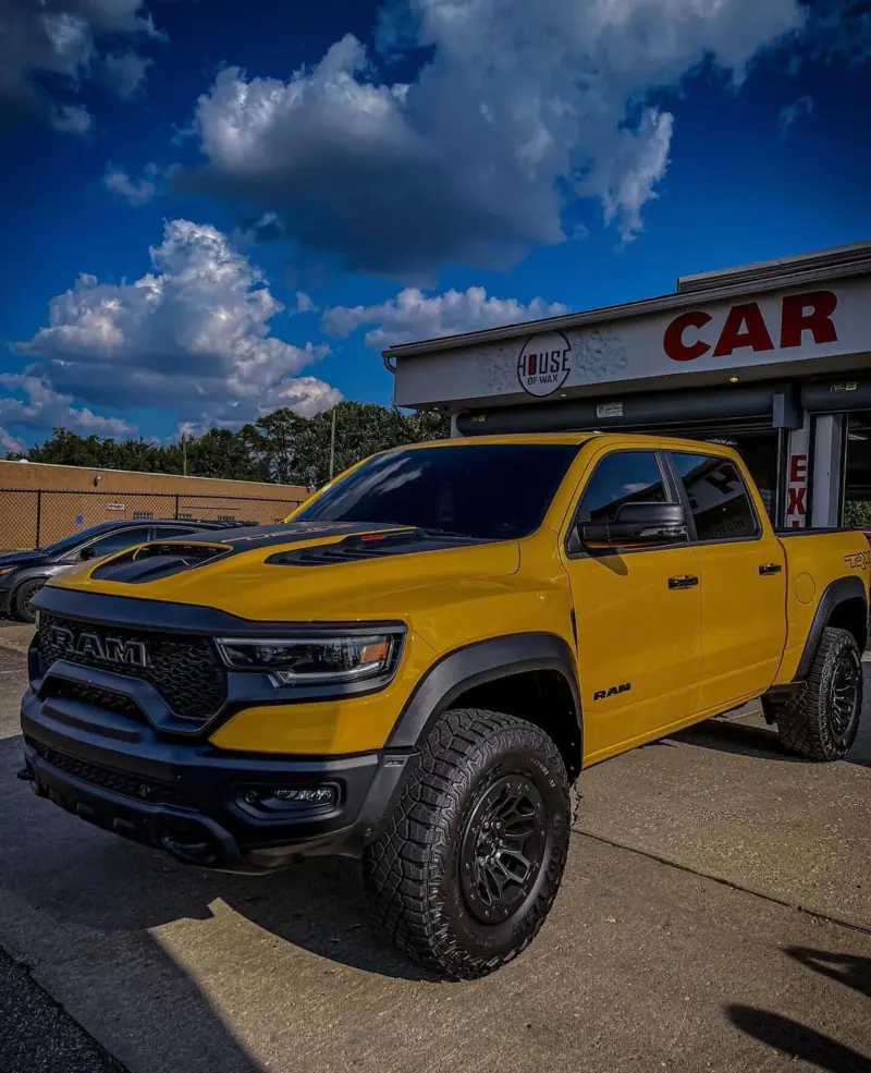 Yellow Ram TRX with a black hood under a dramatic sky, front three quarter view