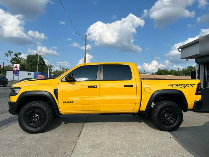 Yellow Ram TRX with a black hood, side view under a blue sky