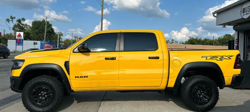 Yellow Ram TRX with a black hood, side view, wide crop
